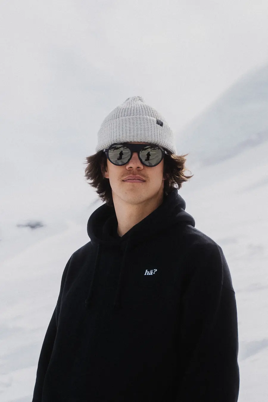 Junger Mann mit heller Mütze und verspiegelter Sonnenbrille auf dem Gletscher