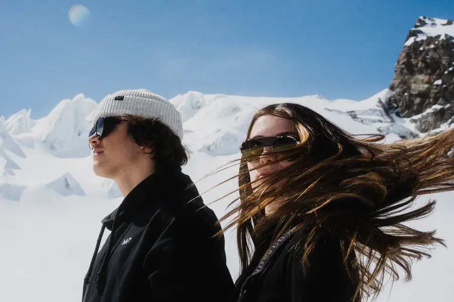 Wind weht der Frau das lange Haar ins Gesicht, daneben der Mann