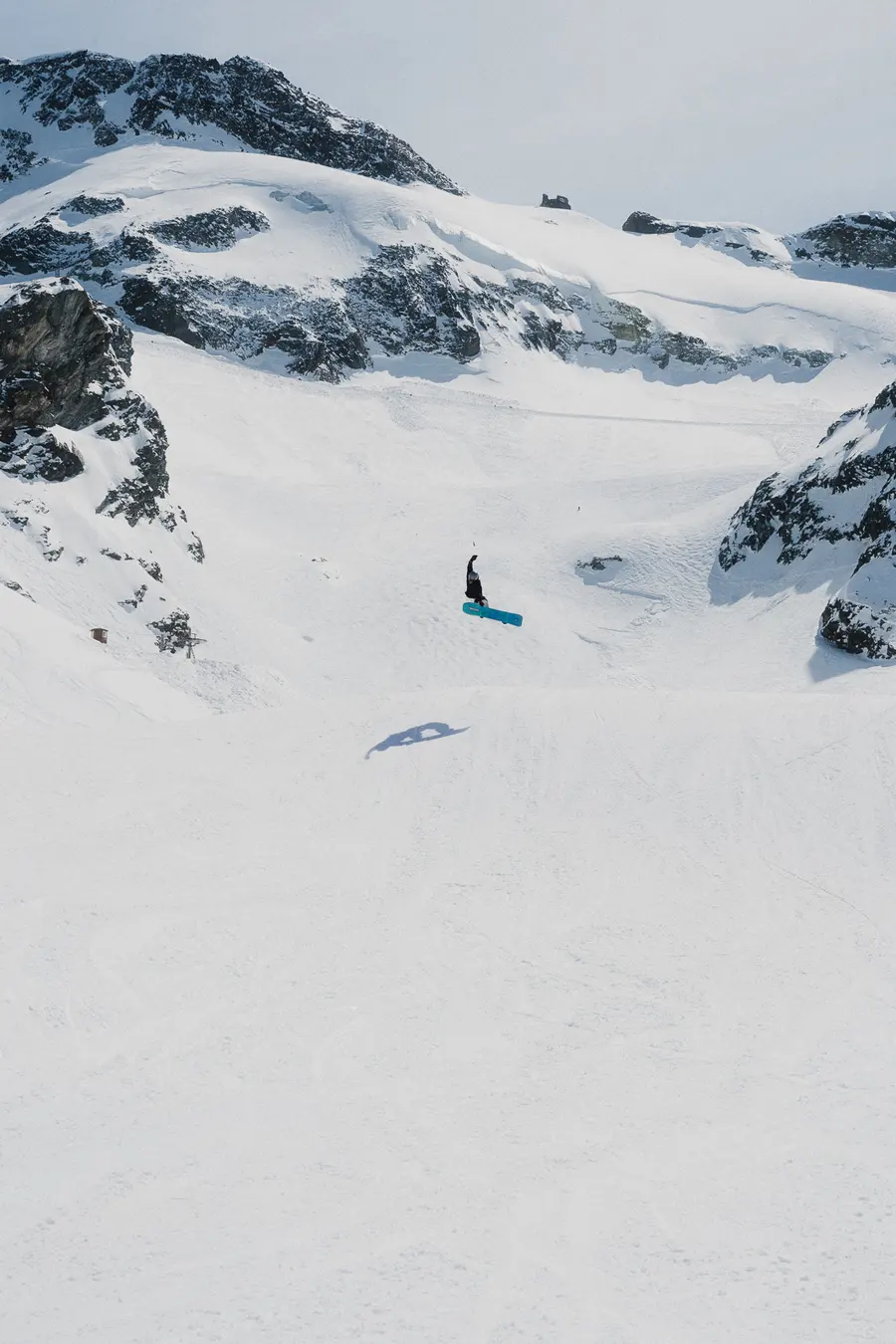 Kleiner Snowboarder in weiter Gletscherlandschaft zwischen Felsgraten