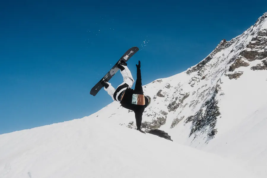 Snowboarder kopfüber bei einem Trick vor tiefblauem Himmel