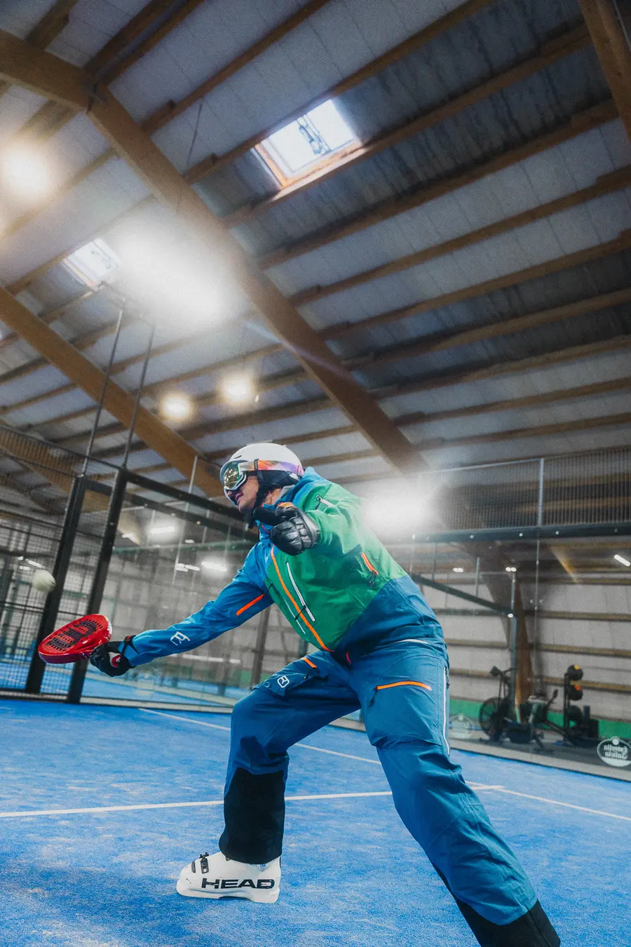 Skifahrer in Skischuhen spielt einen Ball auf dem Indoor-Padelplatz
