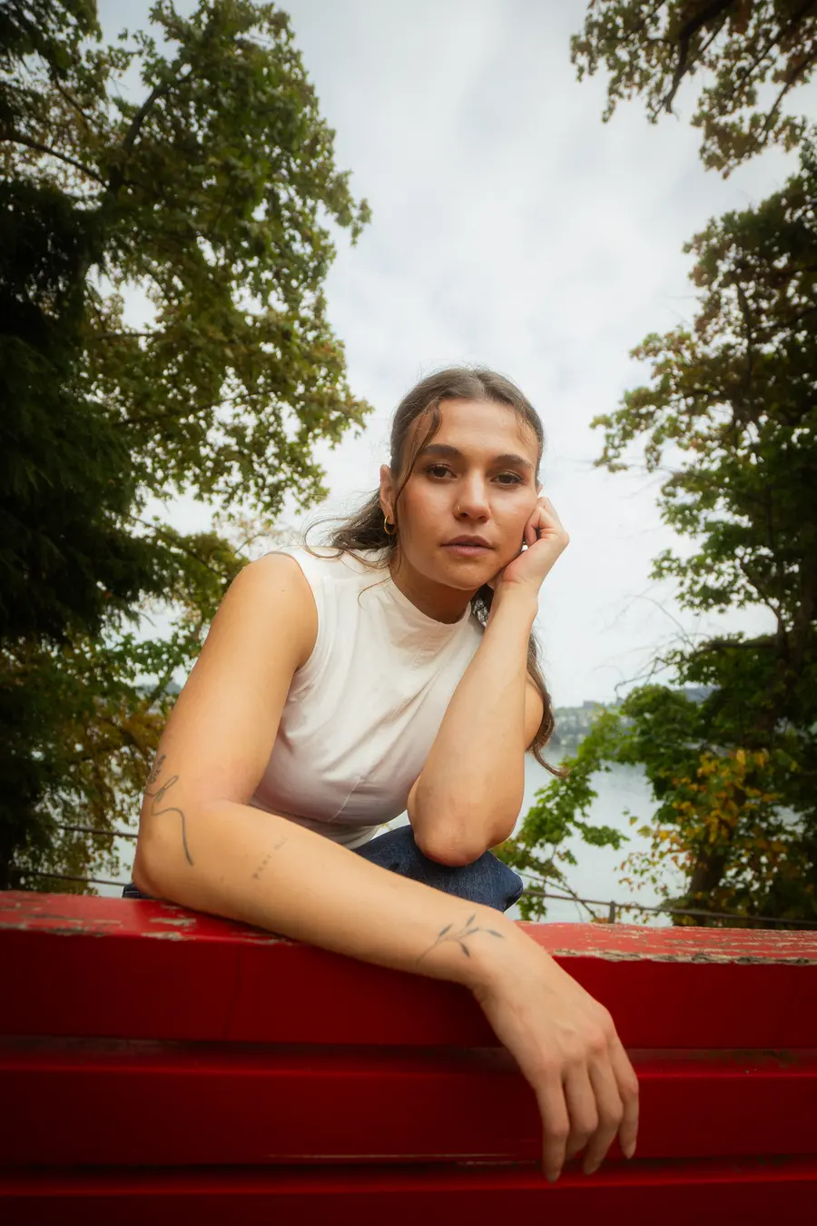 Portrait de la danseuse accoudée à un banc rouge entre les arbres