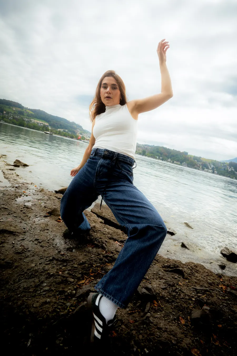 Danseuse en jean et haut blanc sur la rive caillouteuse du lac