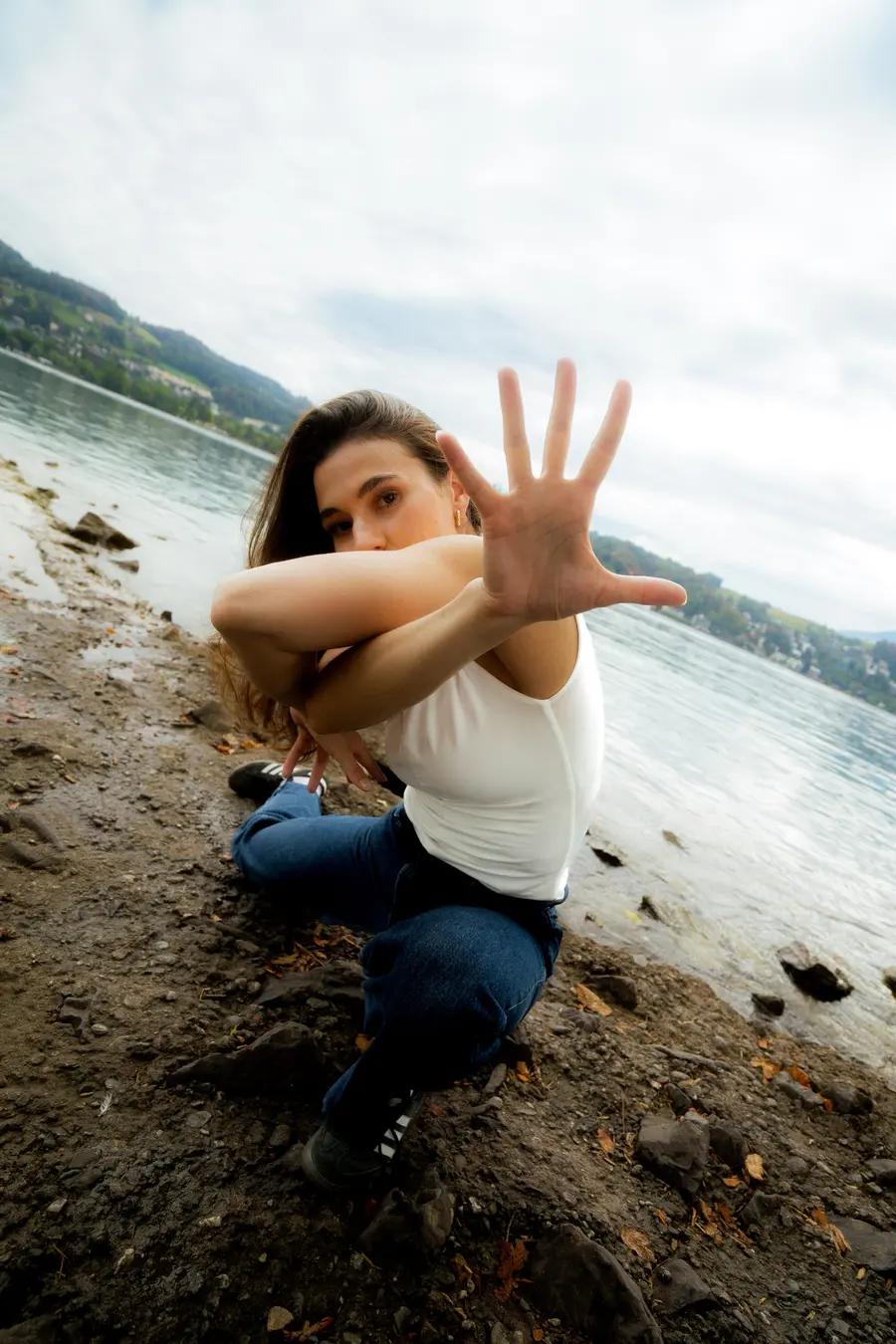 Danseuse assise au bord du lac, main ouverte vers l’objectif