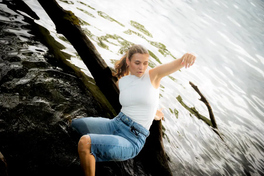 Danseuse en équilibre sur un tronc dans l’eau, bras tendu