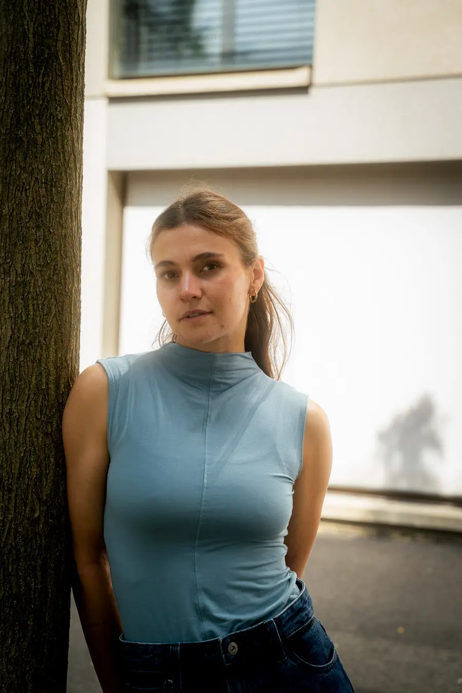 Portrait en haut bleu sans manches, adossée à un tronc d’arbre