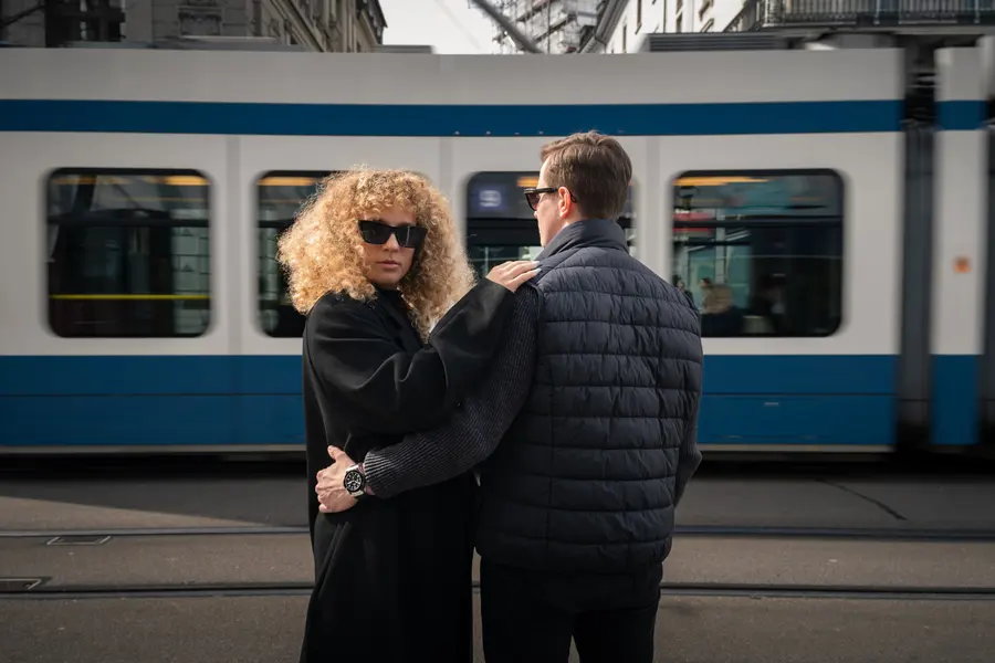 Femme à lunettes regardant par-dessus l’épaule, tram en arrière-plan