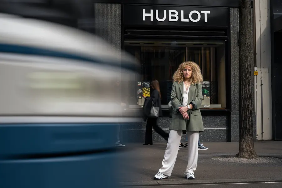 Femme devant la boutique Hublot, un tram passe en flou