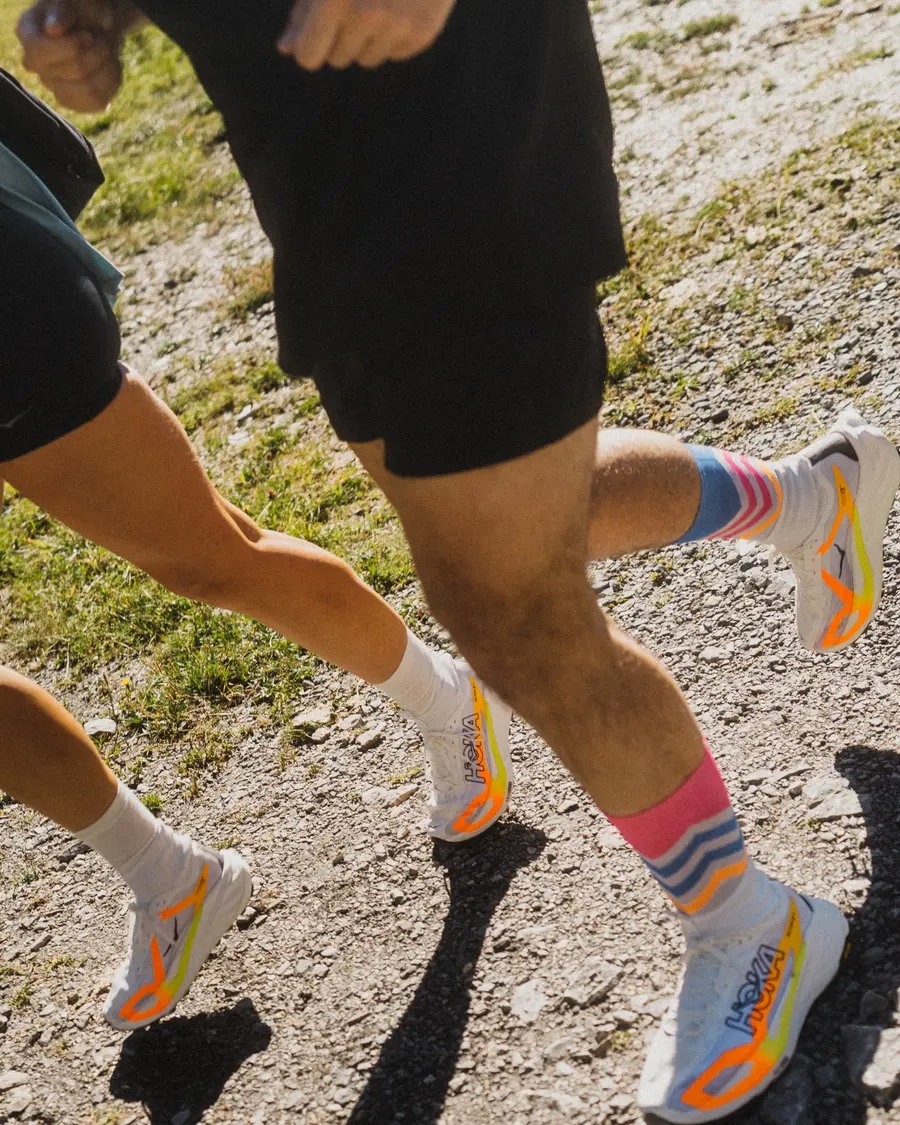 Zwei Läufer mit bunten Socken und Tecton X 4 auf einem Wiesenpfad