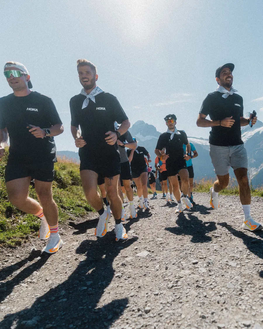 Läufer in schwarzen HOKA-Shirts und Halstüchern laufen auf die Kamera zu