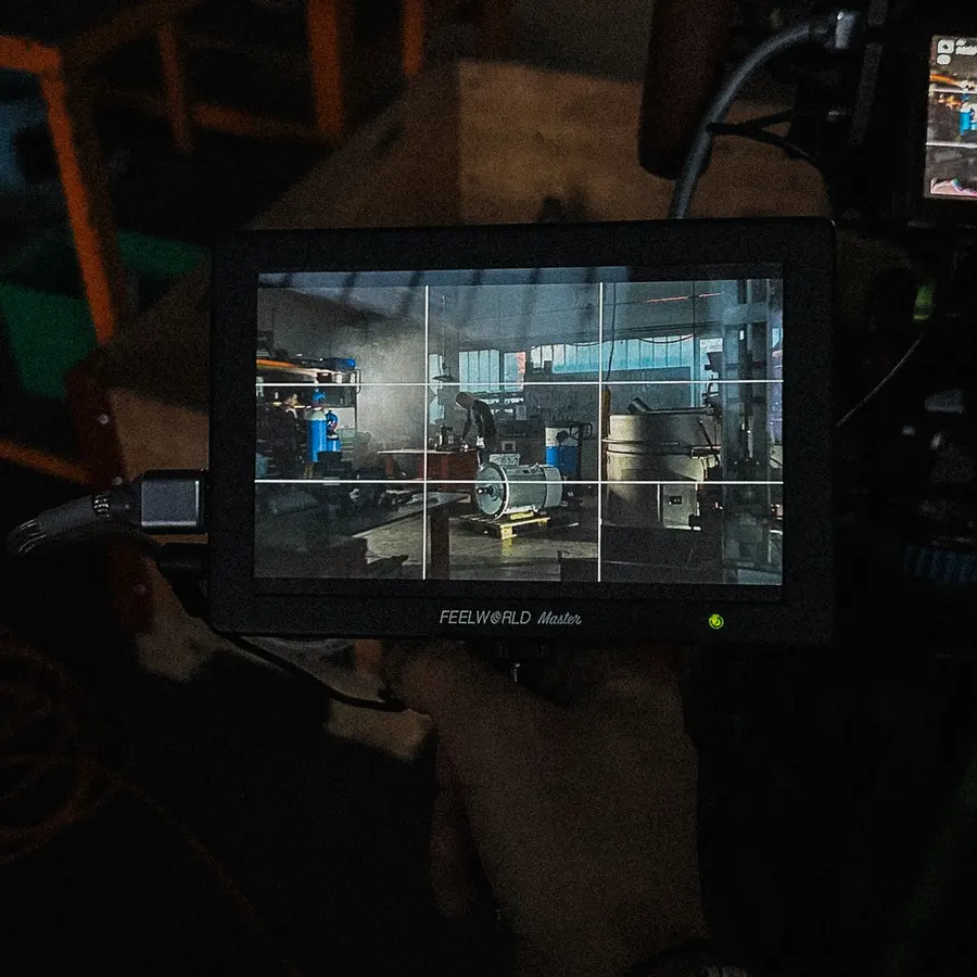 Der Monitor mit Raster zeigt eine Werkstattszene im Halbdunkel