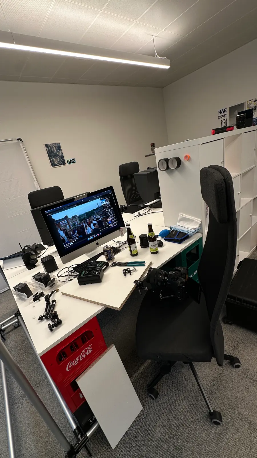 Schnittplatz im Büro: ein Filmbild auf dem Bildschirm, Kamera, Zubehör und Bierflaschen auf dem Tisch