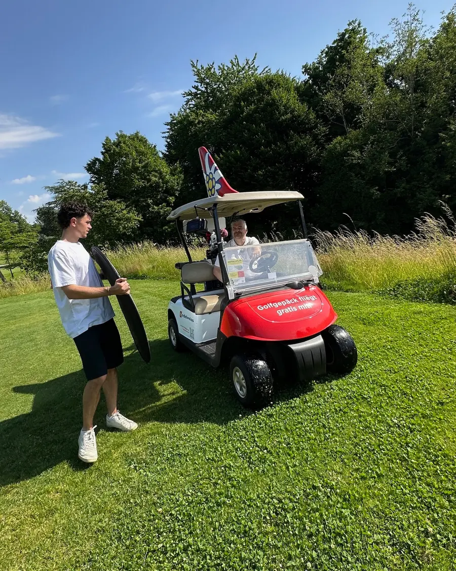 Auf dem Golfplatz: jemand aus dem Team mit einem Reflektor neben einem Golfwagen