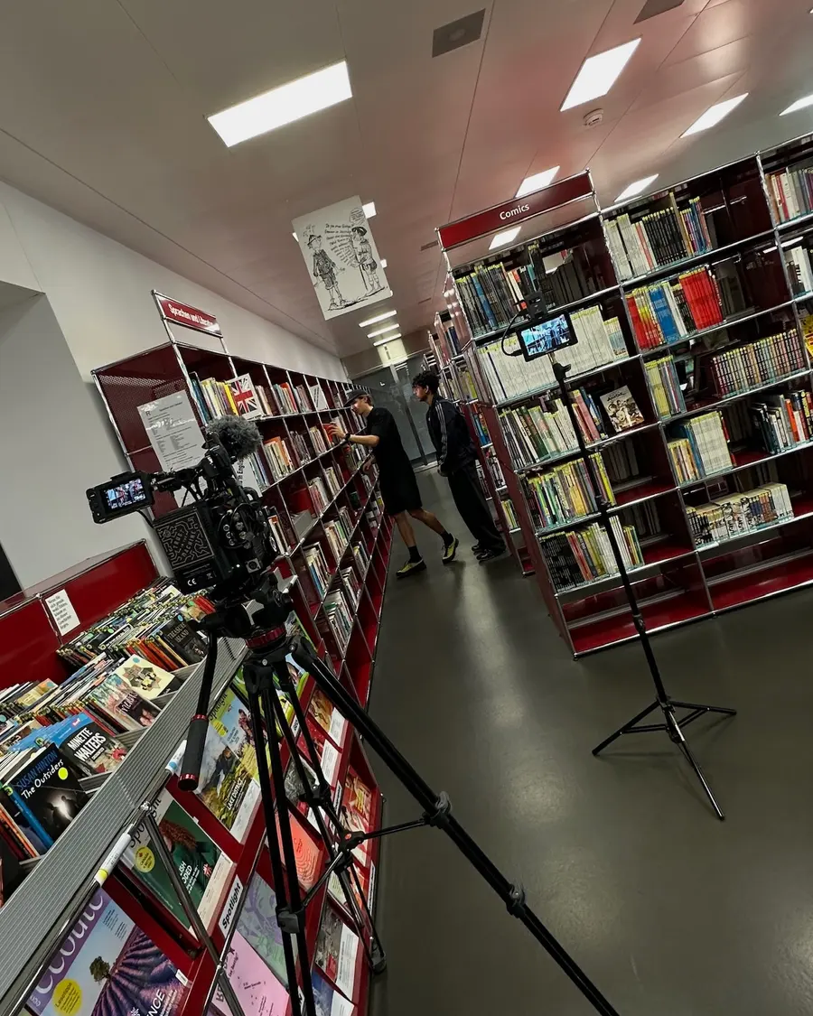 Zwei Kameras auf Stativen zwischen den Comicregalen einer Bibliothek