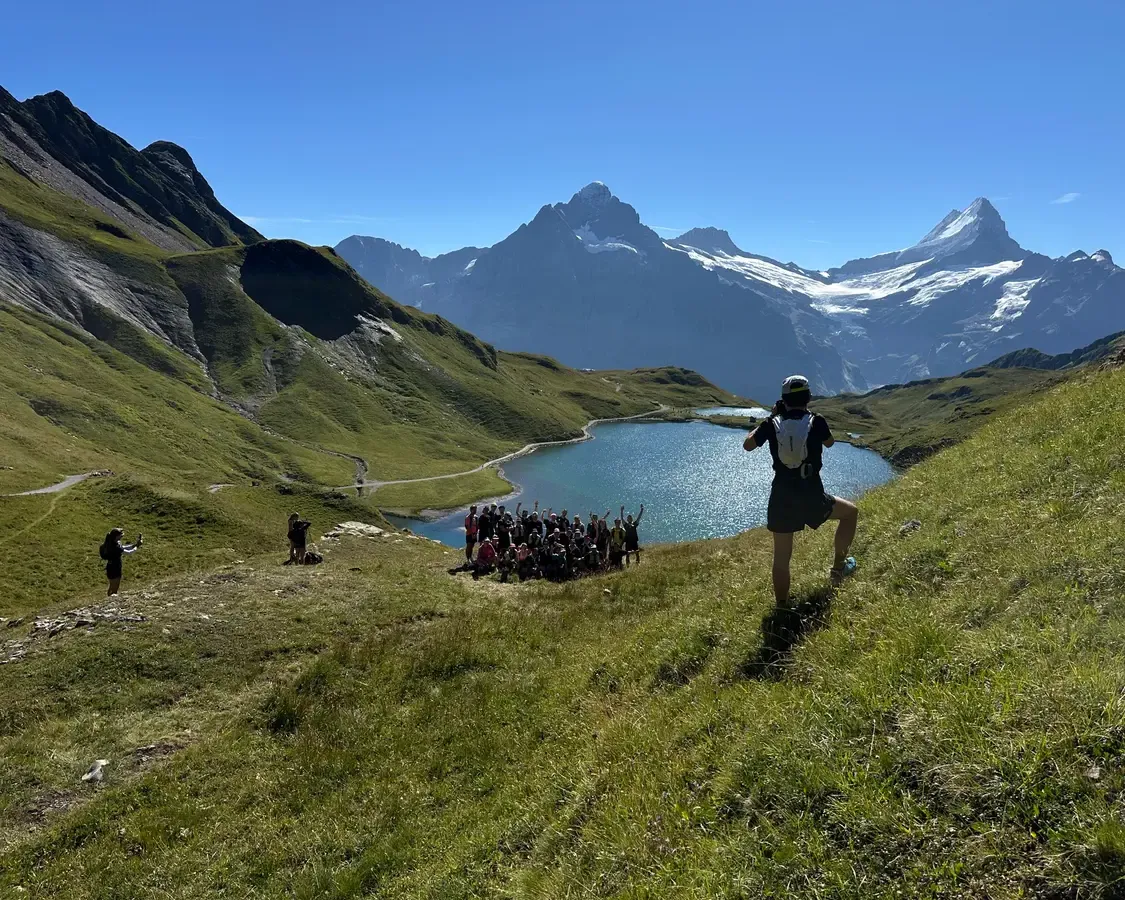 Trailrunner an einem Hang über einem Bergsee, dahinter Felsgipfel