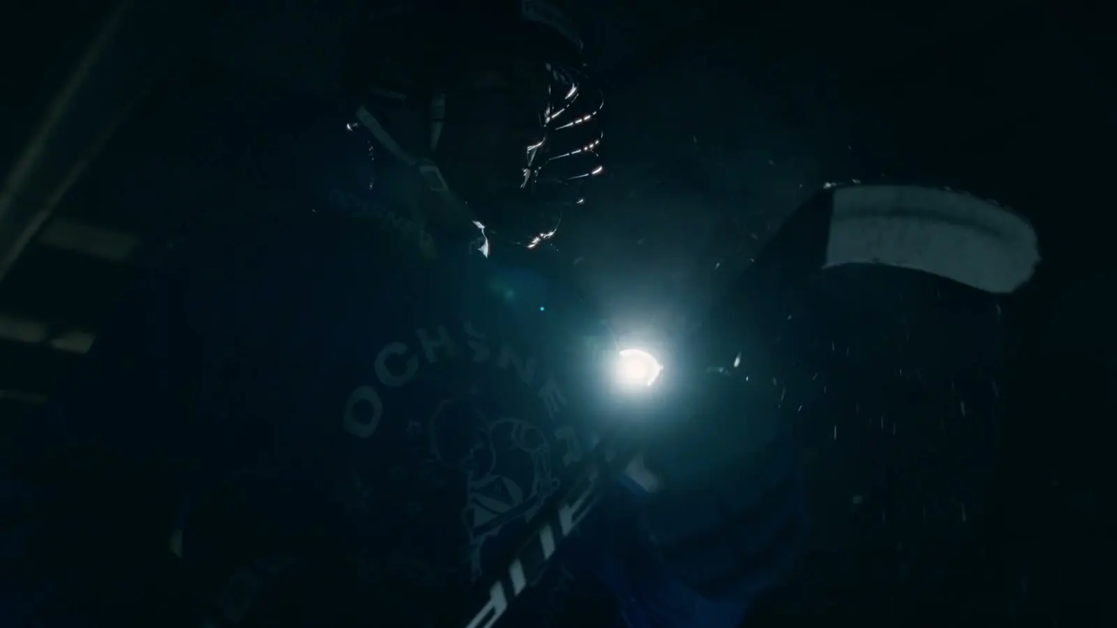 Eishockeyhandschuh und Stock im harten Gegenlicht vor dunklem Hintergrund