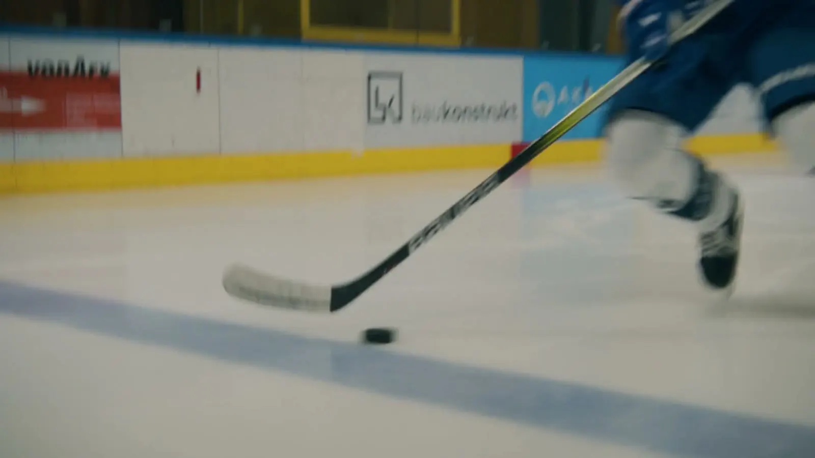 Eishockeyschläger führt den Puck über das Eis