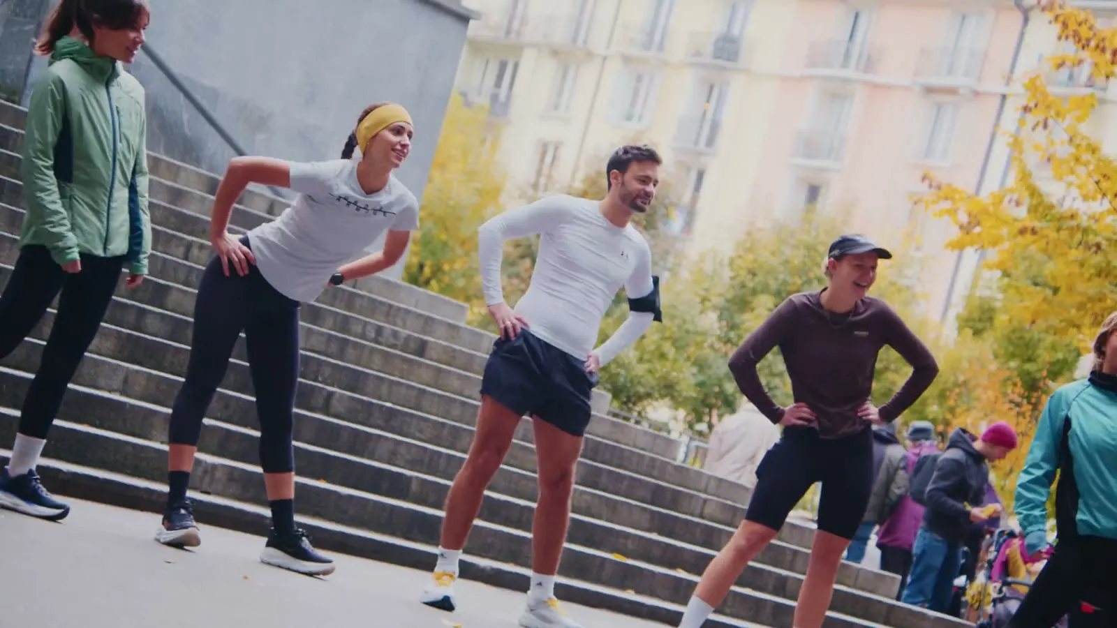 Läuferinnen und Läufer wärmen sich auf einer breiten Treppe in der Stadt auf