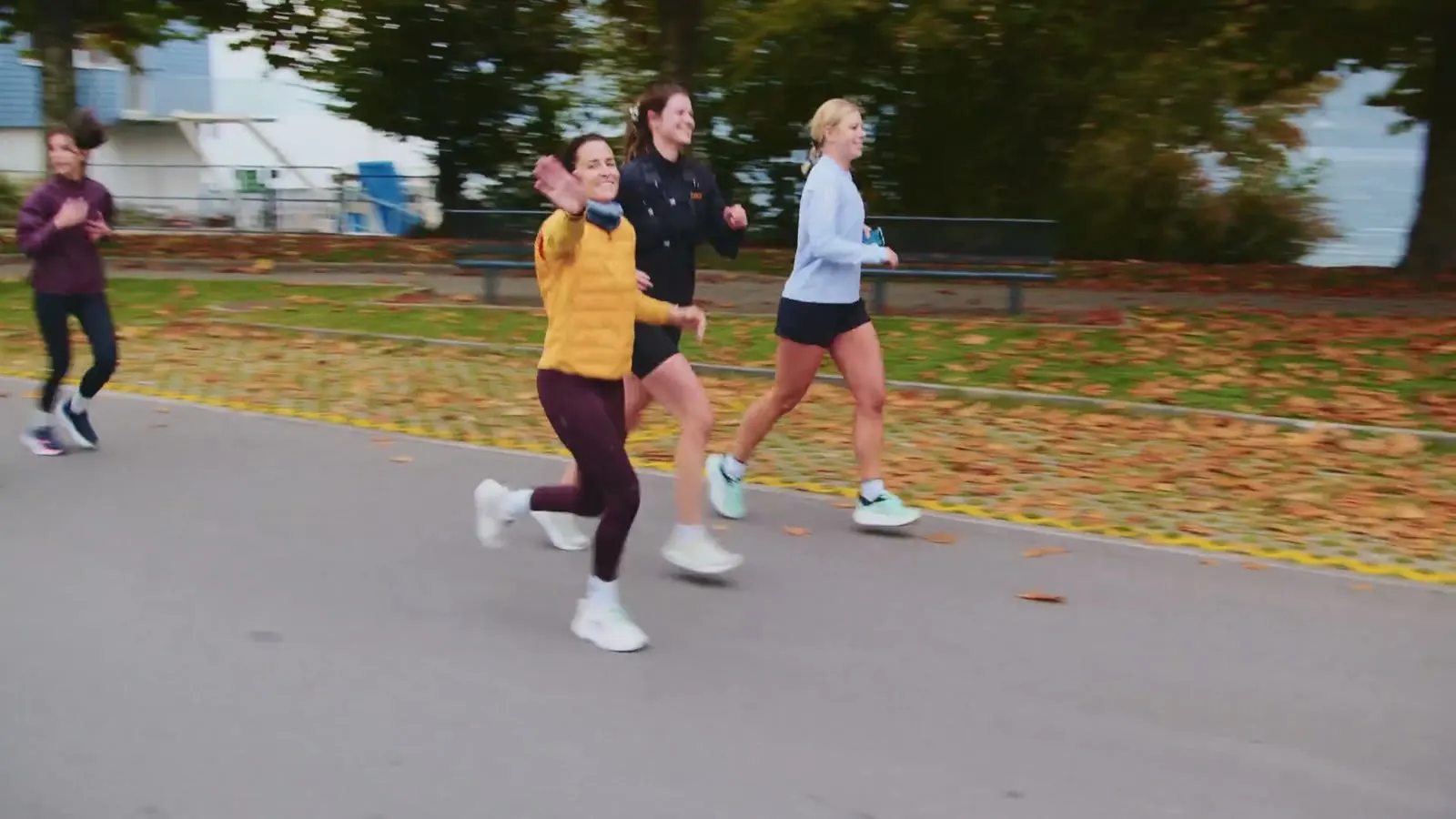 Gruppe läuft auf einem Weg mit Herbstlaub am Seeufer