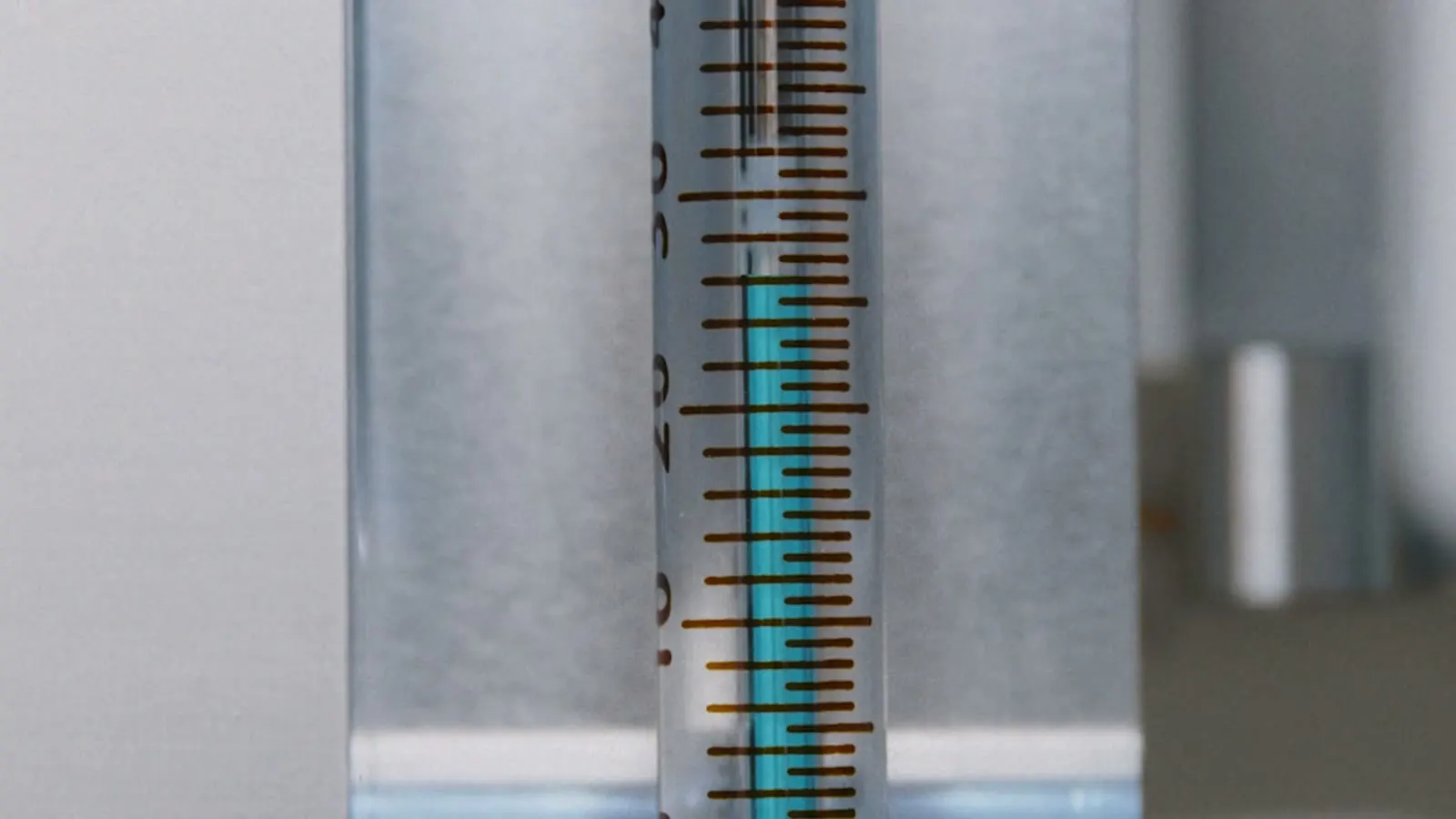 Spritze mit Skala und blauer Flüssigkeit in Nahaufnahme