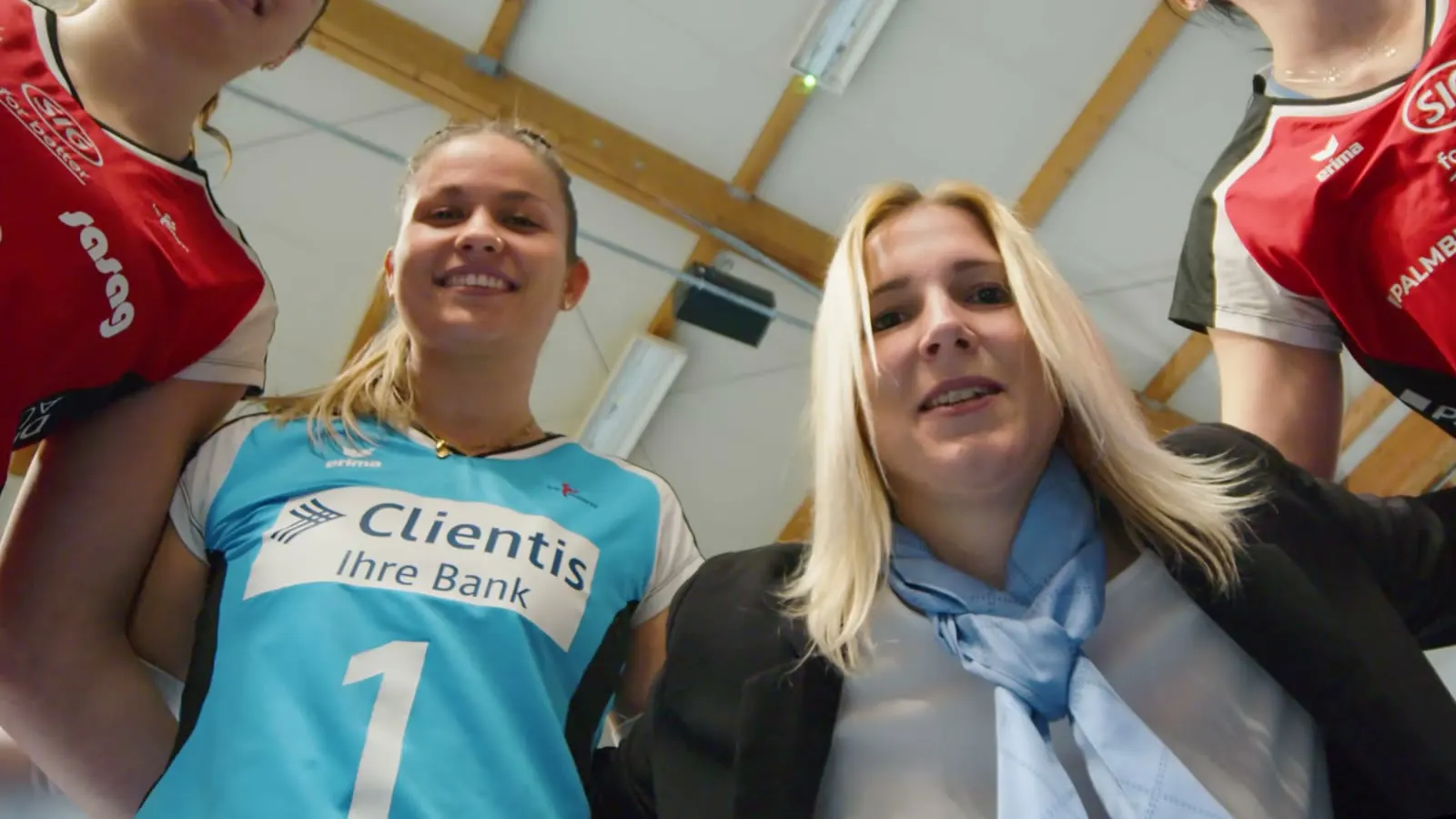 Libera im hellblauen Clientis-Trikot und eine Frau im Blazer blicken von oben in die Kamera