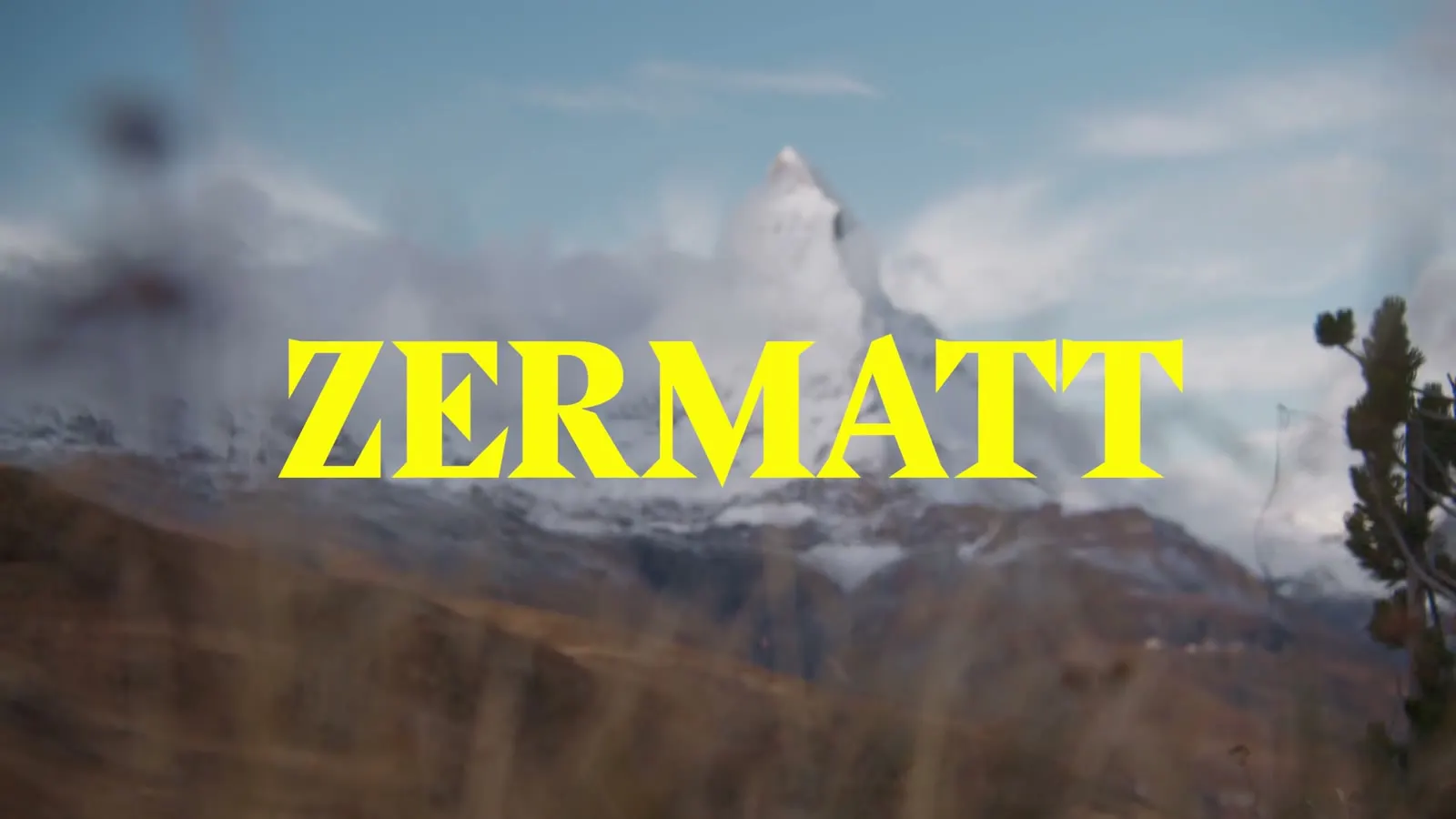 Matterhorn hinter trockenem Berggras mit gelbem Schriftzug Zermatt